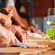 A pair of hands using a knife to chop ingredients on a cutting board